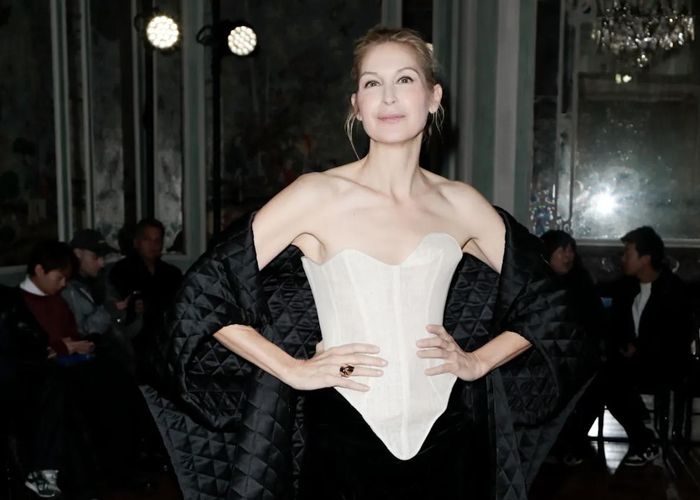 Ngồi trên hàng ghế đầu show thời trang của Ashi Studio, diễn viên Kelly Rutherford diện chiếc corset trắng quyến rũ, phối với chân đầm đen chất liệu nhung. Để gia tăng điểm nhấn và giữ ấm cơ thể, cô sử dụng thêm chiếc cape chần bông. Chiếc corset giúp nữ minh tinh khoe khéo xương quai xanh gợi cảm, bờ vai thanh mảnh và cổ cao. Nữ diễn viên thực hiện kiểu tóc búi cao, gọn gàng, tạo khoảng trống ở phần vai, phô diễn nét quyến rũ ở tuổi 55. Ảnh: Antoine Flament.