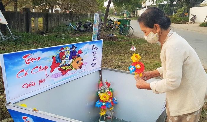 Người dân đưa ông Táo và hoa cũ ra Trạm cá chép siêu tốc đối diện với trụ sở UBND phường Kim Long. Ảnh: LINH TUỆ