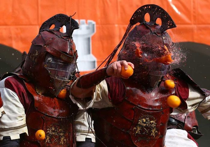 Hàng năm, người dân thị trấn Ivrea sẽ khoác lên mình những bộ trang phục thời trung cổ và phân chia thành 9 đội khác nhau để tham gia vào một cuộc chiến ném cam vô cùng náo nhiệt và độc đáo trong suốt 3 ngày liên tiếp. Để đảm bảo an toàn, phần đầu của những người đứng trên xe ngựa, “mục tiêu” bị tấn công, sẽ được bảo vệ dưới lớp mũ bảo hộ cứng.