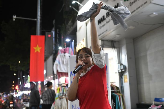  Một nhân viên của cửa hàng quần áo mời khách bằng loa và nhảy múa để thu hút sự chú ý. Cửa hàng này đang có chương trình mua 5 tặng 1, áo thun từ 50.000-150.000 đồng. 