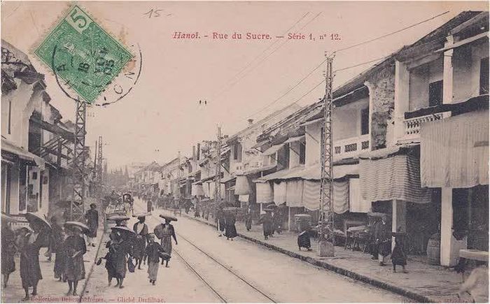 Phố Hàng Đường nhìn về phía chợ Đồng Xuân, với những mái tôn bên trái và cột ống khói nhà máy sợi nằm phía sau chợ