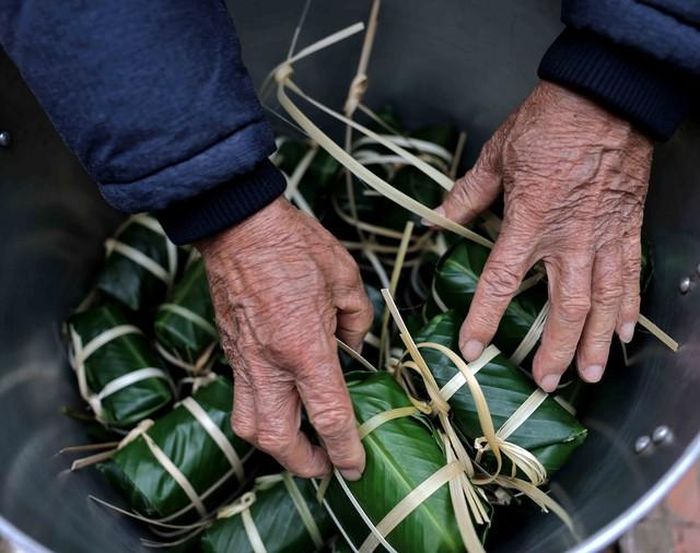 Ông chủ gia đình là người xếp bánh và châm lửa nồi nước đun bánh. Ảnh: Nhật Anh - TTXVN