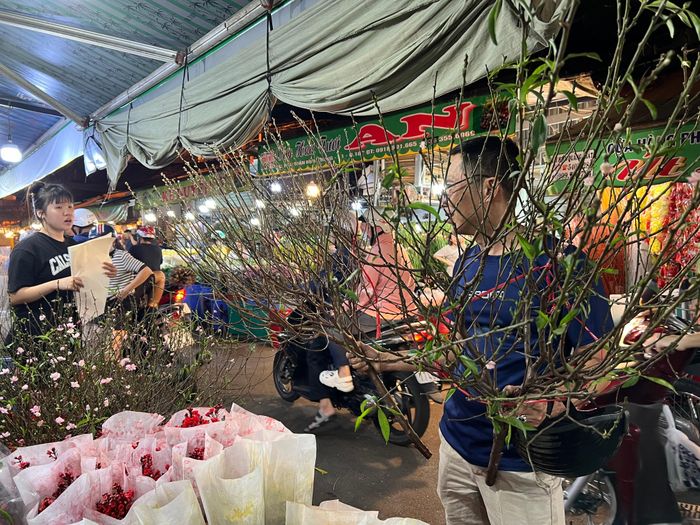 Mua hẳn 2 cành đào về chưng Tết, vị khách cho biết năm nay giá hoa dễ mua hơn mọi năm. Hoa cũng đẹp hơn. Anh đã chọn được 2 cành đào rất ưng ý để trang trí Tết.