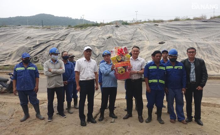 Giám đốc Sở Tài nguyên và Môi trường Phạm Nam Sơn (thứ 5, bên trái sang) tặng quà động viên công nhân vận hành chôn lấp, xử lý rác tại bãi rác Khánh Sơn. Ảnh: HOÀNG HIỆP