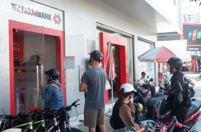 Người dân chờ rút tiền tại cây ATM của Ngân hàng TMCP Kỹ thương Việt Nam (Techcombank) tại ngã tư Ngô Văn Sở - Tôn Đức Thắng (quận Liên Chiểu) sáng 6-2 (27 tháng Chạp). Ảnh: M.Q