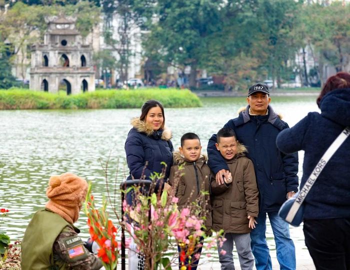 Một gia đình về Hà Nội đón Tết lưu lại khoảnh khắc đẹp bên hồ Hoàn Kiếm với tháp Rùa cổ kính, rêu phong. (Ảnh: Thanh Tùng/TTXVN)