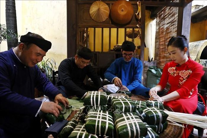 Cứ mỗi dịp Tết đến, Xuân về, các thành viên trong gia đình lại quây quần gói bánh chưng xanh. Ảnh: Minh Quyết/TTXVN