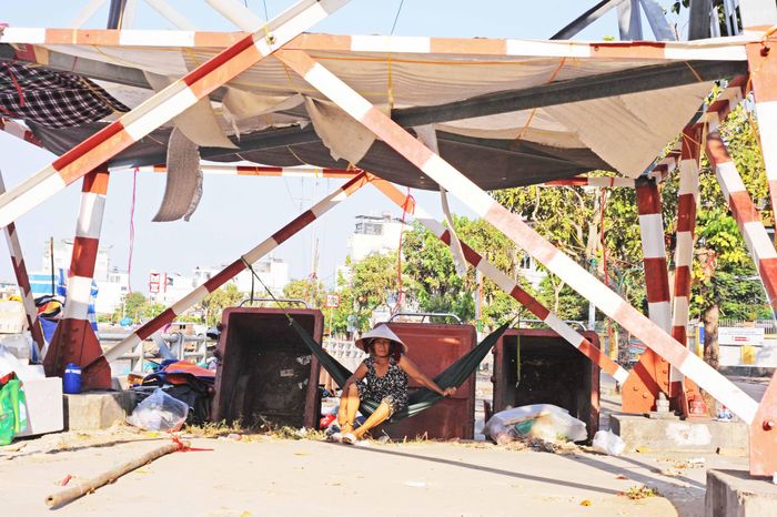 Người phụ nữ tránh nắng dưới chân cột điện nói: "Tết nhất được nghỉ ngơi nhưng cũng mất đi nguồn thu nhập là buôn bán rau cỏ linh tinh nên khó khăn hơn ngày thường". 