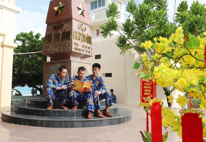 Các chiến sĩ tại đảo Sinh Tồn Đông đọc báo tại cột mốc chủ quyền.