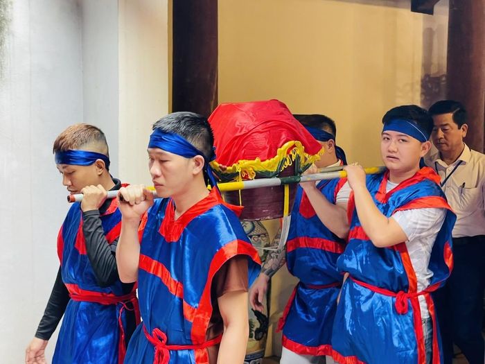 Bốn thanh niên trai tráng ở trong làng rước nước vào điện thờ. 