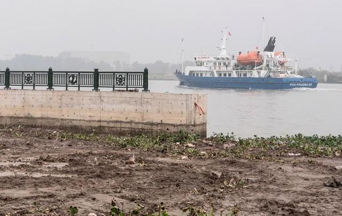 View từ bến phà Bính xưa ra sông Cấm: Một bờ kè bê tông đã lắp sẵn hàng rào bằng gang đúc hình mỏ neo và hoa phượng, dưới sông là một con tàu cũng có tên Hoa Phượng Đỏ đang chạy. Phía tiền cảnh sẽ được san lấp để trở thành công viên…