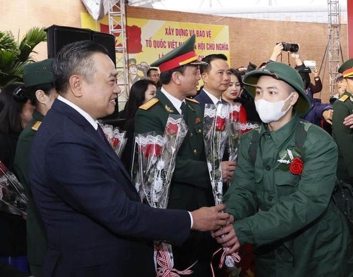 Ông Trần Sỹ Thanh, Chủ tịch UBND thành phố, Chủ tịch Hội đồng Nghĩa vụ quân sự thành phố Hà Nội Trần Sỹ Thanh tặng hoa, động viên các tân binh quận Hoàng Mai. Ảnh: Văn Điệp - TTXVN