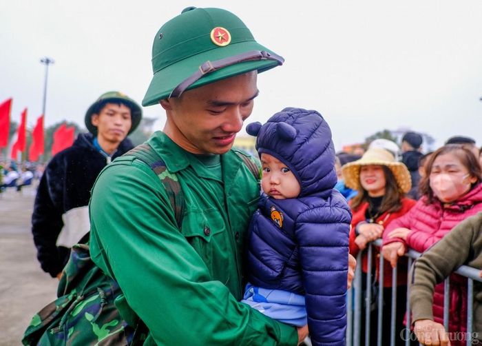 Tân binh Nguyễn Văn Duy (24 tuổi) bế trên tay con trai mình trước khi lên đường làm nhiệm vụ thiêng liêng của Tổ quốc. "Em khá buồn khi phải rời xa gia đình cũng như vợ và đặc biệt là con trai em. Nhưng vì nhiệm vụ quốc gia và cũng là tự hào của thanh niên quê hương Hai Bà Trưng em đã sẵn sàng để rèn luyện trở thành một anh Bộ đội Cụ Hồ. Đây cũng sẽ là một trong những kỷ niệm để em có thể kể cho con trai em khi bạn ấy lớn", tân binh Nguyễn Văn Duy nói