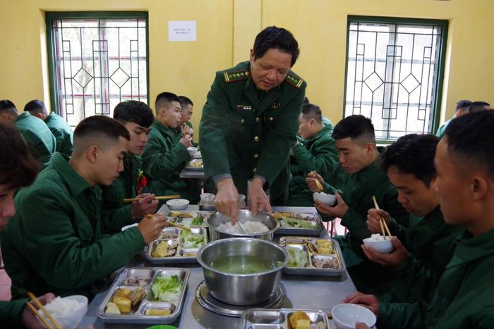 Đại tá Trịnh Hữu Đức, Chỉ huy trưởng Trung tâm Huấn luyện BĐBP xuống bếp ăn, động viên tân binh trong ngày đầu nhập ngũ. Ảnh: Đoàn Chung