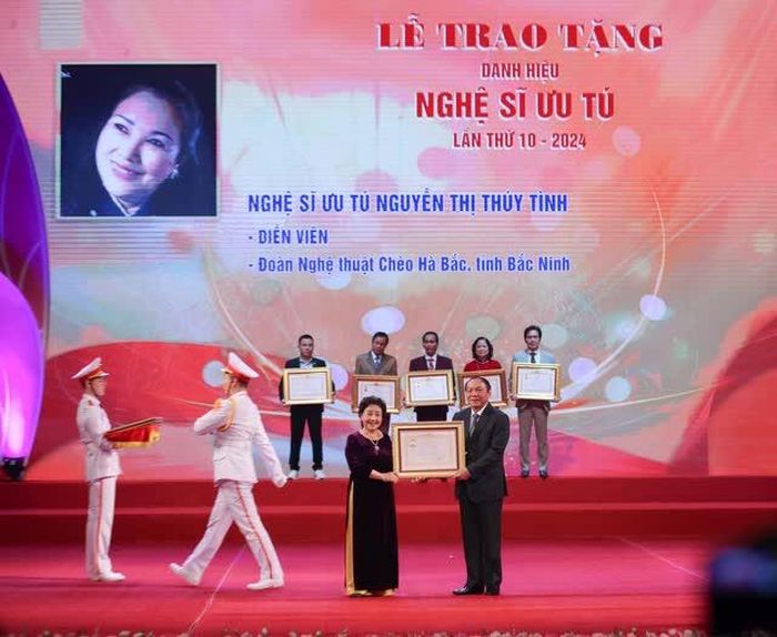 Bộ trưởng Nguyễn Văn Hùng trao danh hiệu "Nghệ sĩ ưu tú" cho nghệ sĩ Nguyễn Thị Thúy Tình, đoàn nghệ thuật chèo Hà Bắc (Bắc Ninh). Ảnh: Thanh Tùng - TTXVN
