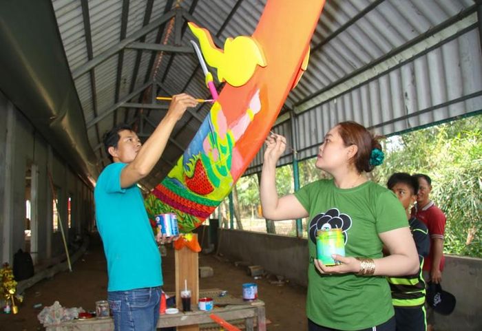 Vợ chồng nghệ nhân vẽ hoa văn trang trí chiếc ghe ngo chùa Ompuyear (chùa Nhu Gia, Sóc Trăng).