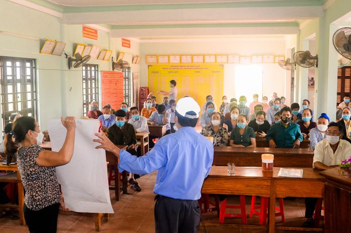Người dân được các đầu mối liên lạc cộng đồng truyền thông về phòng tránh bom mìn - Ảnh: T.L