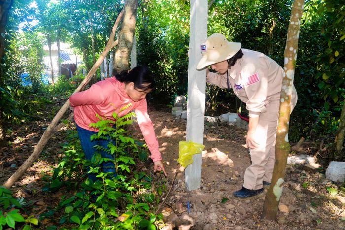 Chị Ánh Tuyết (trái) báo cáo với nhân viên của MAG về một vật nổ được người dân phát hiện - Ảnh: T.L