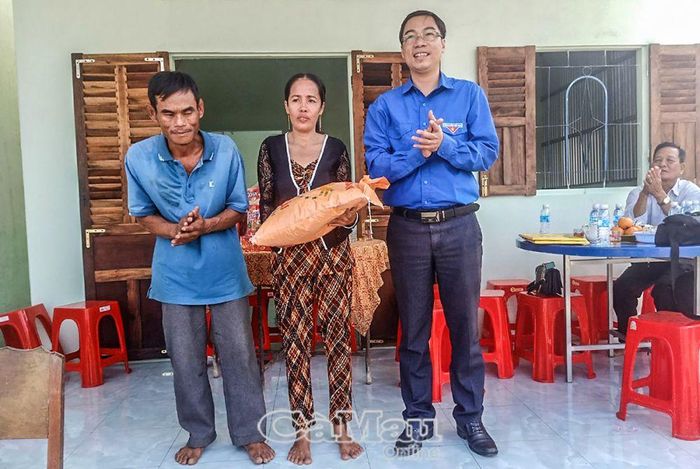 Anh Lê Chí Linh, Bí thư Ðoàn khối Dân Chính Ðảng, trao quà cho hộ ông Lâm Văn Danh và bà Nguyễn Thị Mận, nhân buổi bàn giao nhà do Ðoàn khối Dân Chính Ðảng vận động hỗ trợ.
