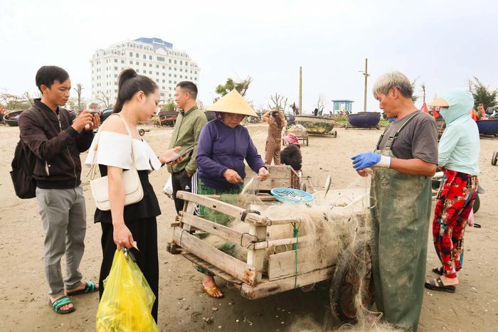  Du khách thích thú xem ngư dân gỡ lưới sau chuyến đi mủng. Ảnh: T.P 