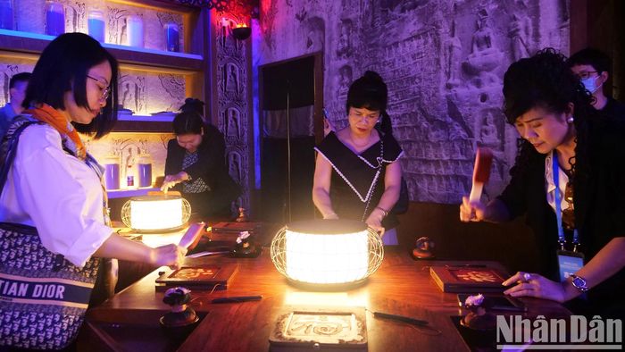 Du khách trải nghiệm in dập mực chữ nổi - một di sản văn hóa phi vật thể của Trung Quốc.