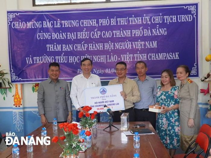 Phó Bí thư Thành ủy, Chủ tịch UBND thành phố Lê Trung Chinh (thứ hai, bên trái) trao tặng 50 triệu đồng để hỗ trợ hoạt động Hội Người Việt Nam tỉnh Champasak. ẢNH: S.TRUNG
