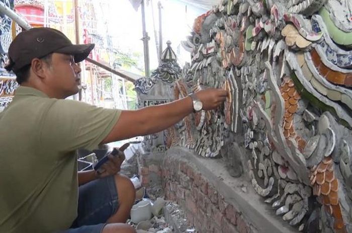 Lựa được gam màu phù hợp, nghệ nhân dùng một chiếc kìm cắt kim loại nhỏ để cắt gọt mảnh sứ cho thật bo tròn, khớp với họa tiết trên bức phù điêu.