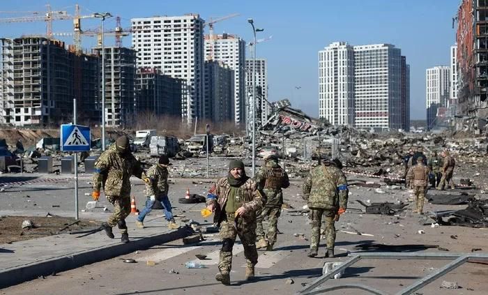 Các binh sĩ Ukraine đứng trước một trung tâm thương mại bị phá hủy ở Kiev (Ảnh: Getty Images).