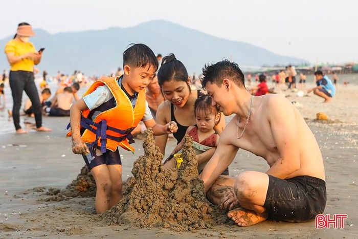 Một gia đình trẻ cùng chơi trò xây lâu đài cát.