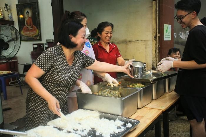 Các tình nguyện viên vui vẻ cùng nhau chuẩn bị những suất cơm miễn phí cho bà con