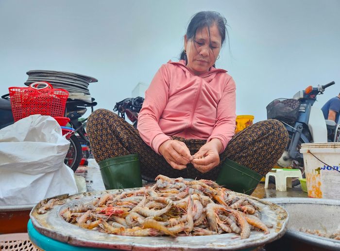 "Tàu thuyền về sớm nên 2 mẹ con phải dậy sớm từ trước 4h để ra bến. Nếu không ra sớm thì không chọn mua được nhiều, ở đây tiểu thương họ đến thu mua nhiều lắm. Chậm chân là hết phần. Sau khi mua xong tôi làm sạch hải sản để con gái mang đi các chợ bán", bà Dương Thị Thế (58 tuổi, trú khối Yên Định, phường Nghi Thủy) chia sẻ.