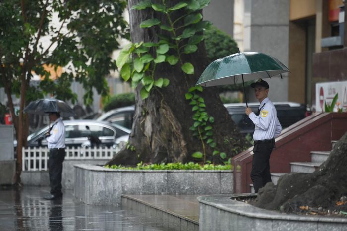 Bảo vệ của tòa nhà số 233 Đồng Khởi (quận 1) cầm ô đón khách ra vào trong cơn mưa chiều 4/5.