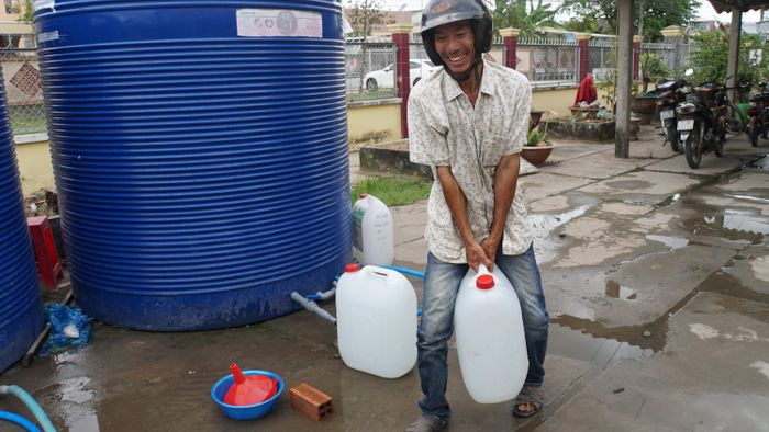  Ông Nguyễn Văn Thảo ở xã An Hóa (Châu Thành, Bến Tre) bê từng thùng nước ngọt. Ảnh: HÒA HỘI