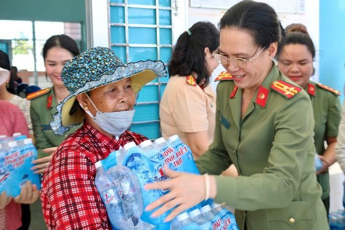 Thượng tá Nguyễn Thị Hạnh, Trưởng ban Phụ nữ Công an TPHCM, trao tặng nước uống đóng chai cho bà con tỉnh Tiền Giang.