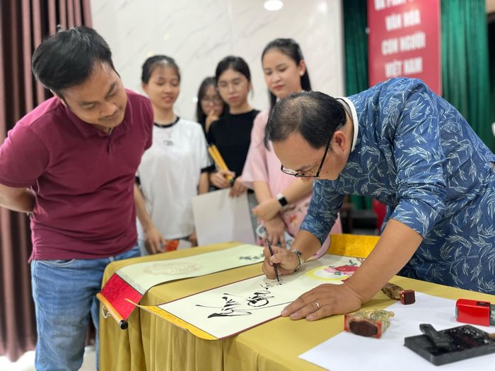  Th.S Nguyễn Hiếu Tín (Trưởng bộ môn Du lịch, Khoa Khoa học Xã hội và Nhân văn, Trường Đại học Tôn Đức Thắng) hướng dẫn viết thư pháp cho khách tham quan Bảo tàng TPHCM 