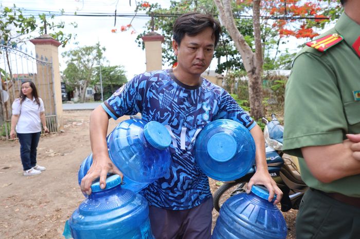 Một thanh niên mang bình nhựa đến hứng nước về cho gia đình