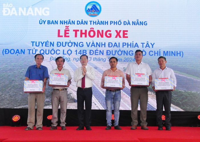 Bí thư Thành ủy Nguyễn Văn Quảng (thứ 3, bên trái qua) tặng quà cho các hộ dân đã di dời, bàn giao mặt bằng thi công tuyến đường. Ảnh: THÀNH LÂN