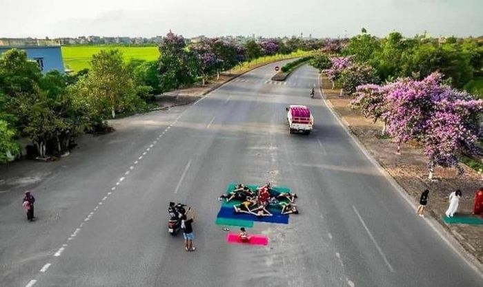 Nhóm phụ nữ tạo dáng yoga ở giữa đường để chụp ảnh với hoa bằng lăng. Ảnh: Huyện Kiến Xương