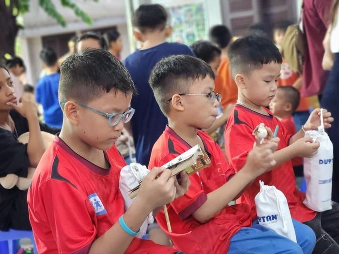 Các em học sinh thích thú với phần quà của mình.
