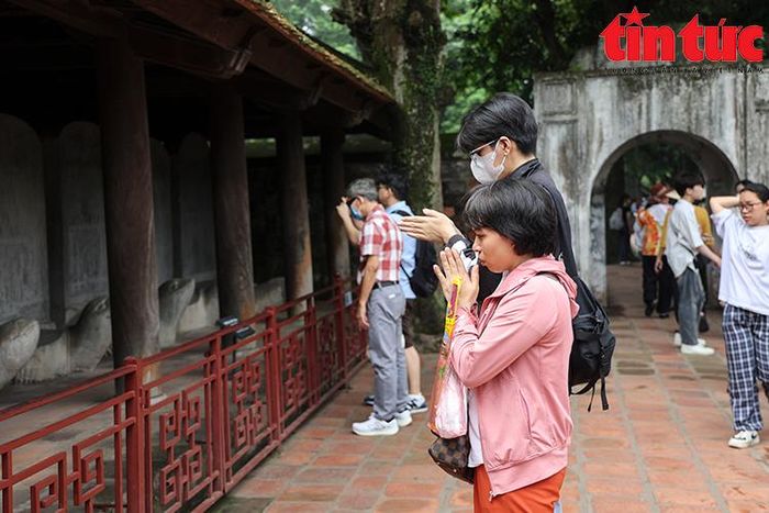 Ngay từ cổng vào đã có nhiều người chắp tay khấn cầu trước hàng bia tiến sĩ.