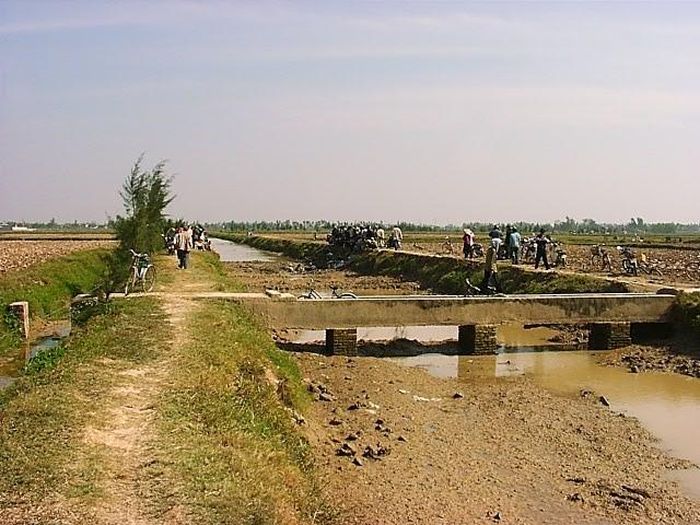 Quang cảnh cuộc khai quật Châu Can 2000. Phía dưới mương là vị trí các nhà khảo cổ học đang khai quật hai mộ thân cây khoét rỗng Đông Sơn. Phần đất trên bờ mương phía bên phải là nơi phân bố "làng cổ Châu Can"chỉ rộng khoảng 500m2. Năm 2001, chúng tôi cùng các nhà địa chất Nhật Bản khoan một mũi địa chất ở đây