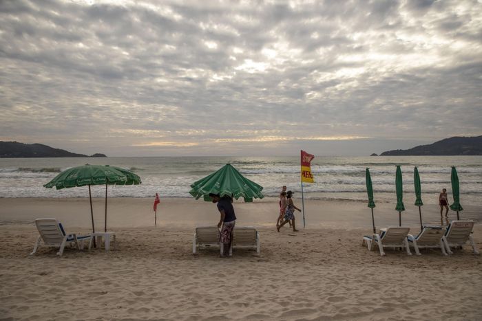  Một người bán hàng tháo ô vào cuối ngày tại bãi biển Patong ở Phuket, Thái Lan. Ảnh: Bloomberg.