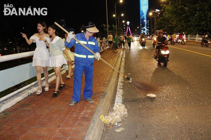  Công nhân Công ty CP Môi trường đô thị Đà Nẵng tổng dọn vệ sinh, thu gom rác trên cầu Sông Hàn. Ảnh: HOÀNG HIỆP 