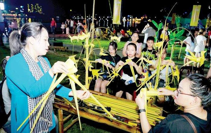 Du khách tập xếp lá dừa tại một gian hàng trên Bến Bạch Đằng, trong khuôn khổ Lễ hội sông nước TPHCM lần 2 Ảnh: HOÀNG HÙNG