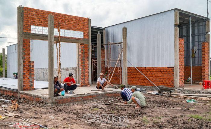 Ông Nguyễn Văn Cảnh (bìa phải) rất vui mừng khi được vào khu tái định cư xây cất nhà.