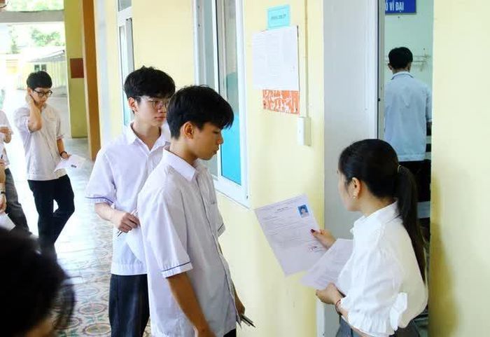 Giám thị kiểm tra thẻ dự thi của các thí sinh trước khi vào phòng thi tại điểm thi Trường THPT Đào Duy Từ (thành phố Đồng Hới, Quảng Bình). Ảnh: Tá Chuyên - TTXVN