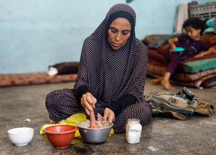 Một phụ nữ Palestine chuẩn bị đồ ăn tại lớp học nơi bà trú ẩn ở Khan Younis. Hơn 20% số người cho biết họ đã nhịn ăn cả ngày lẫn đêm. Ảnh: Mohammed Salem/Reuters.