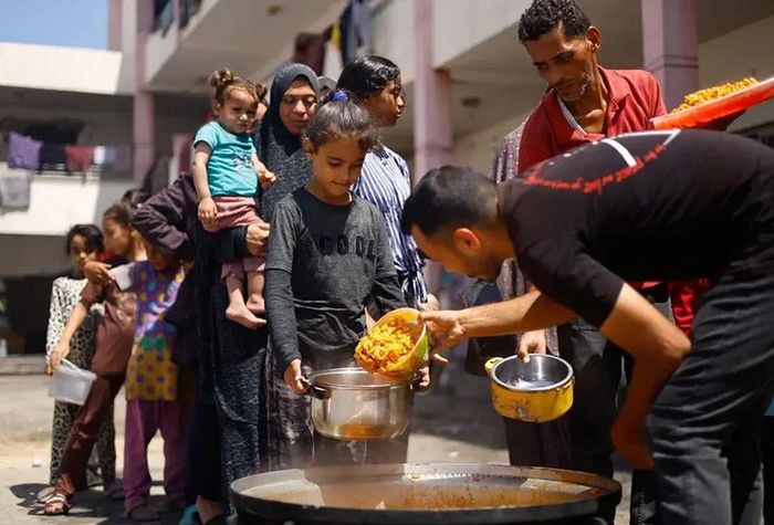 Người Palestine tụ tập để nhận thực phẩm do một bếp từ thiện nấu trong bối cảnh khan hiếm thực phẩm ở Khan Younis, miền nam Gaza. Ảnh: Mohammed Salem/Reuters