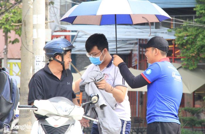 Tình nguyện viên tại điểm thị Trường trung học phổ thông chuyên Lương Thế Vinh hỗ trợ che nắng cho thí sinh. Ảnh: Nga Sơn