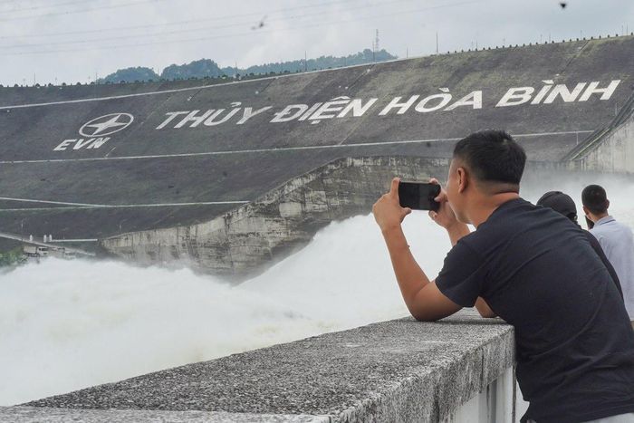 Nhiều người đến đập thủy điện Hòa Bình chụp ảnh, ngắm cảnh, thậm chí tiến sát khu vực xả lũ để chứng kiến dòng nước cuồn cuộn sau khi Nhà máy Thủy điện Hòa Bình xả đáy một cửa xả. (Ảnh: Đức Nguyễn)